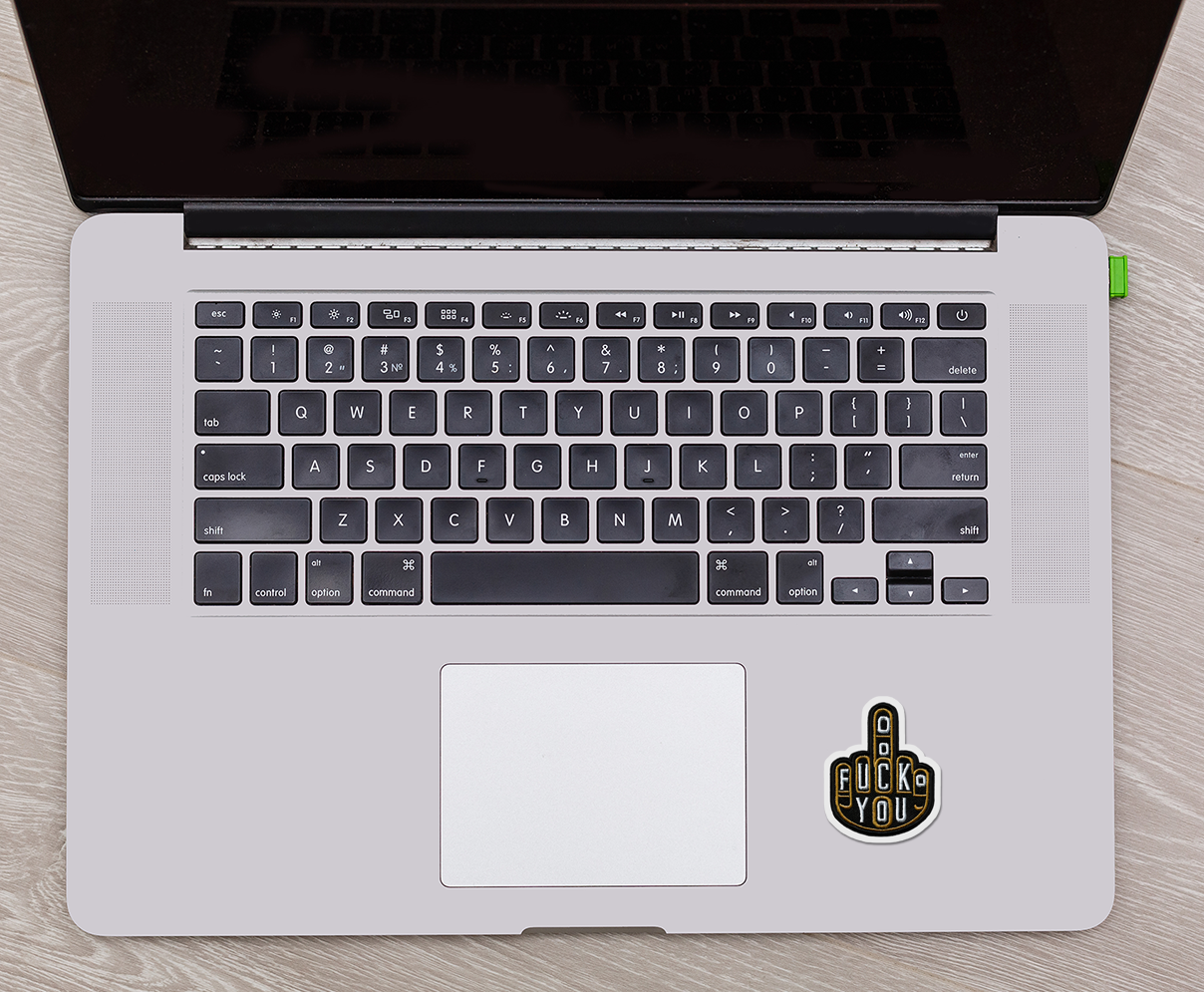 Laptop with a sticker on the trackpad on a wooden surface