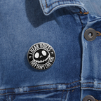 Black and white button with creepy smiley face and text “I Hear Voices, They Don’t Like You.” Glossy finish, metal backing on a denim jacket.