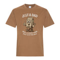 Caramel colored graphic T-shirt featuring a distressed vintage-style cartoon milk carton wearing a shirt and tie, giving a thumbs-up, with “Just A Dad” above and “Who Always Came Back With The Milk.” below in white retro lettering.